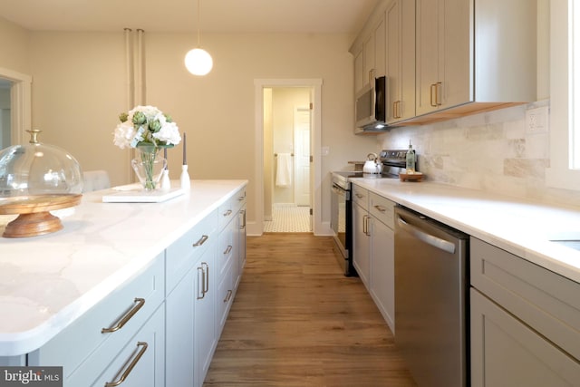 kitchen with tasteful backsplash, light stone counters, light wood-style flooring, hanging light fixtures, and stainless steel appliances