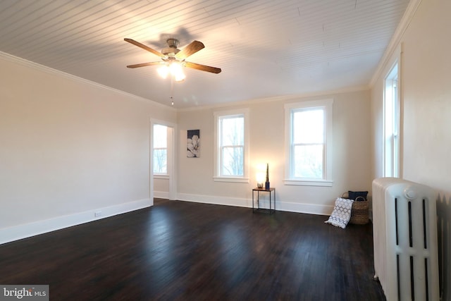 spare room with radiator, baseboards, dark wood finished floors, ceiling fan, and ornamental molding