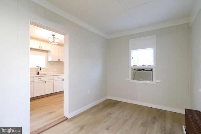 unfurnished dining area featuring light wood-style flooring, cooling unit, baseboards, and a sink