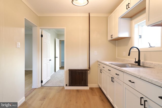 kitchen featuring white cabinetry, light countertops, radiator heating unit, and a sink