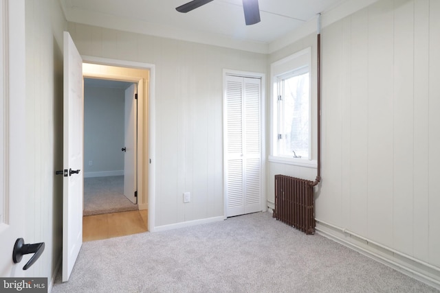 unfurnished bedroom with radiator, baseboards, ceiling fan, a closet, and carpet flooring