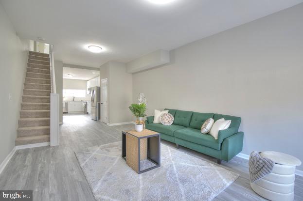 429 N Lakewood Ave, Baltimore, MD 21224 - living room with stairway, baseboards, and light wood-style floors