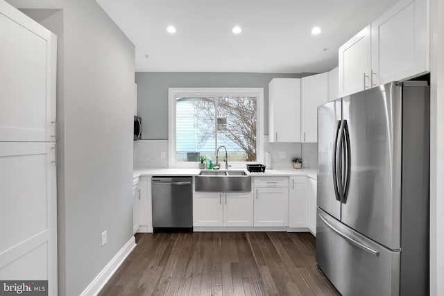 kitchen with a sink, stainless steel appliances, dark wood-type flooring, light countertops, and white cabinetry