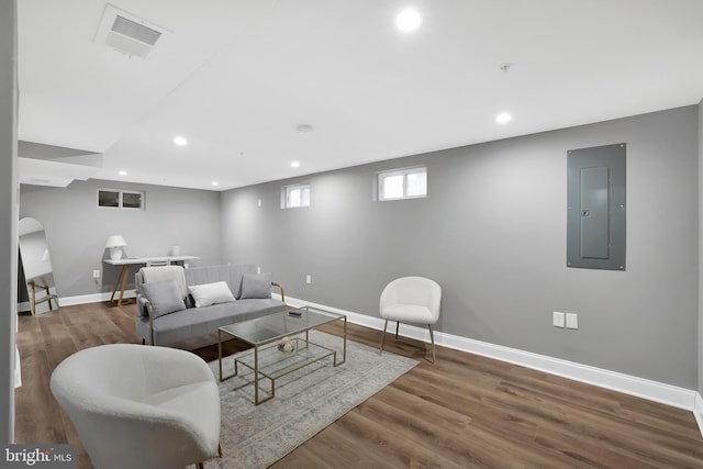 living room featuring electric panel, visible vents, baseboards, and wood finished floors