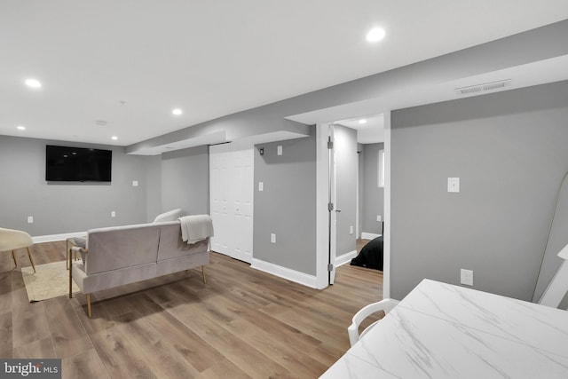 living area with recessed lighting, visible vents, light wood finished floors, and baseboards