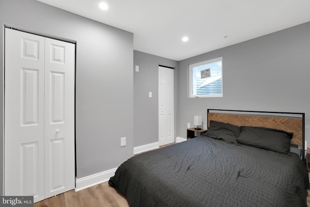 bedroom featuring recessed lighting, light wood-style floors, multiple closets, and baseboards