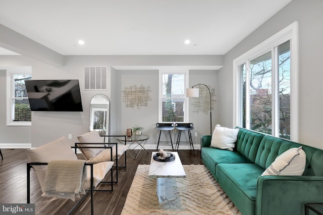 living room featuring dark wood-type flooring, baseboards, visible vents, and a wealth of natural light