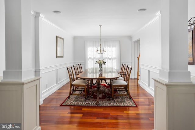 dining room with hardwood / wood-style floors, a notable chandelier, ornamental molding, and a decorative wall