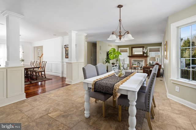 dining area featuring a notable chandelier, a decorative wall, wainscoting, and decorative columns