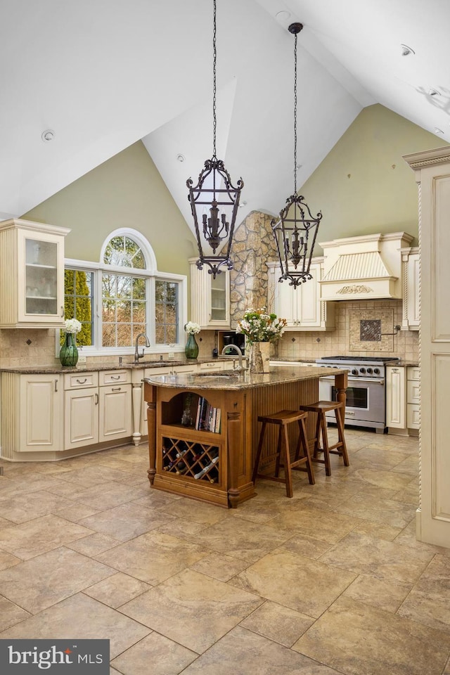 kitchen with premium range hood, stainless steel range, glass insert cabinets, a kitchen breakfast bar, and a chandelier