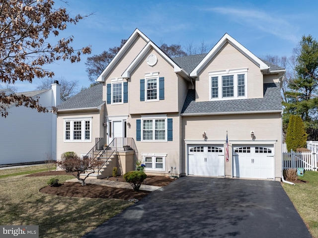 view of front of home with driveway, a shingled roof, a garage, and fence