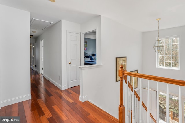 corridor featuring baseboards, an upstairs landing, attic access, and hardwood / wood-style flooring