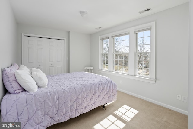 bedroom with carpet flooring, baseboards, visible vents, and a closet