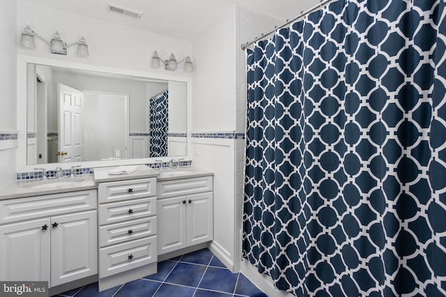 bathroom with a sink, visible vents, double vanity, and tile patterned floors