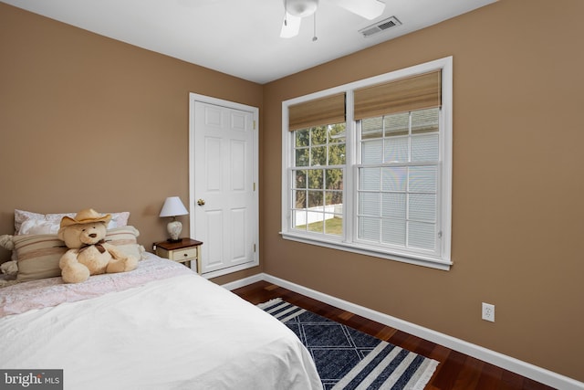 bedroom featuring dark wood-style floors, visible vents, a ceiling fan, and baseboards