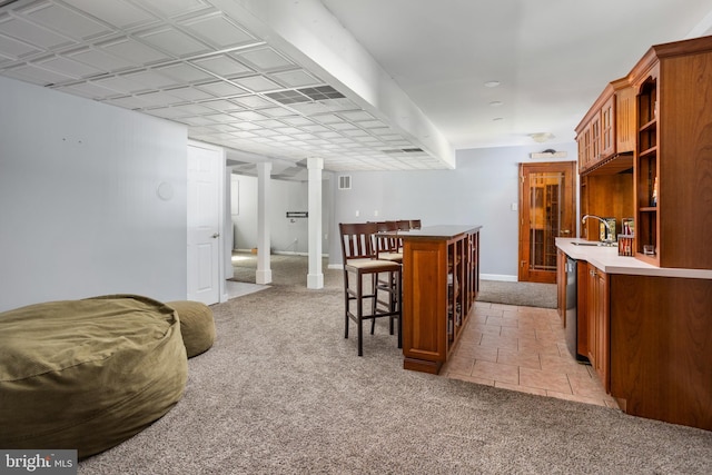 kitchen with a sink, brown cabinets, light colored carpet, and black dishwasher