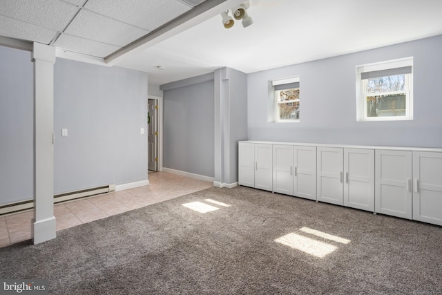 below grade area featuring tile patterned flooring, baseboards, carpet floors, and a baseboard radiator