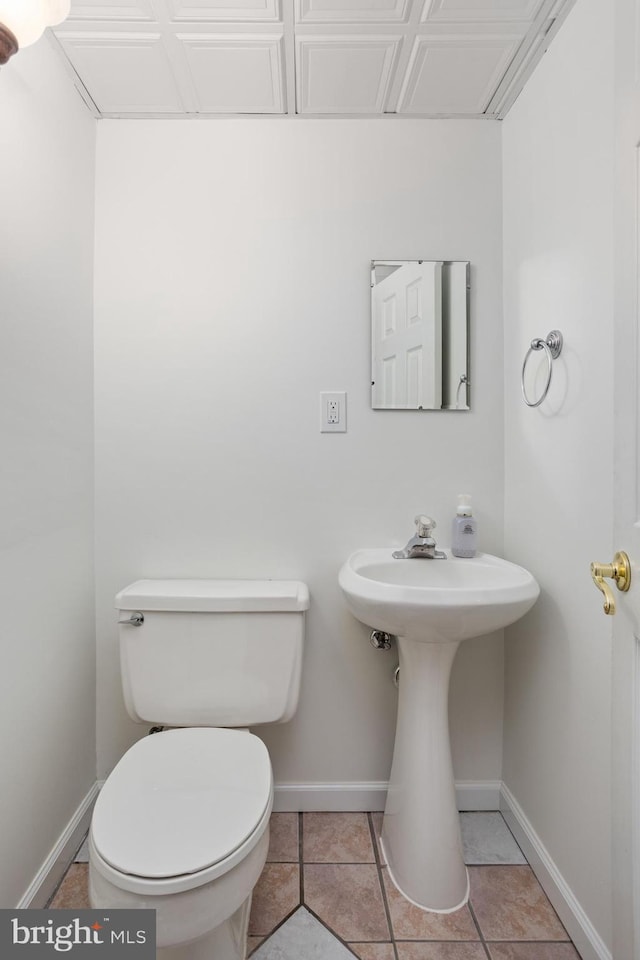 bathroom featuring baseboards, toilet, and tile patterned flooring