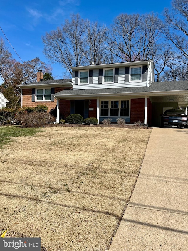 view of front of property with a chimney, a carport, concrete driveway, a front lawn, and brick siding