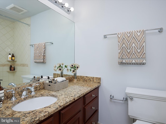 bathroom with visible vents, toilet, walk in shower, and vanity