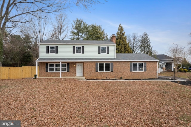 traditional home featuring a gate, fence, brick siding, and a chimney