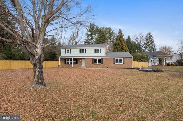 traditional home featuring brick siding, a chimney, and fence