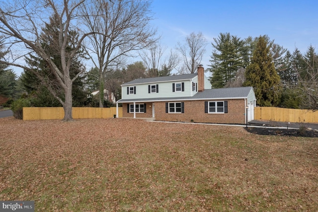 view of front facade with brick siding, a chimney, and fence