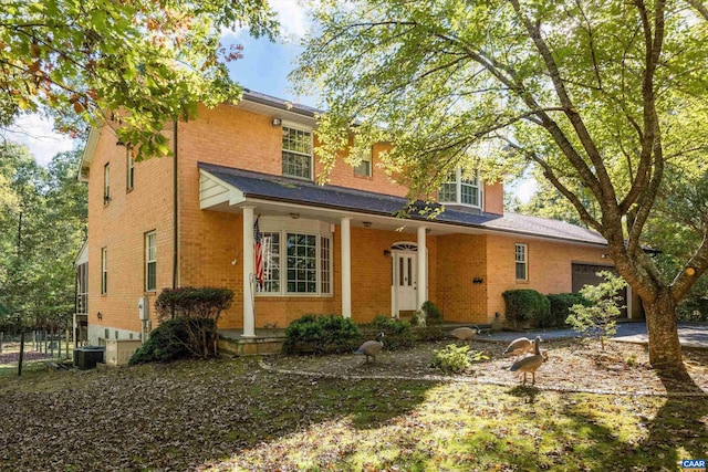 traditional home with brick siding, cooling unit, a porch, and a garage