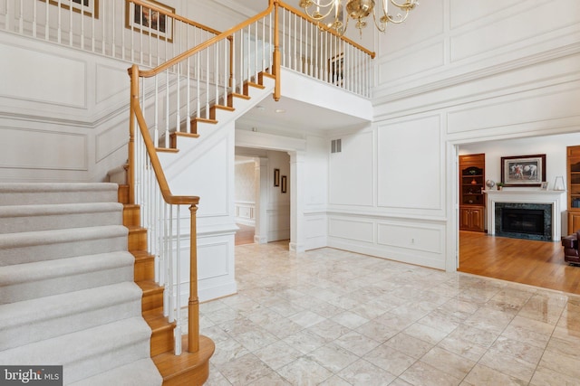 interior space with a decorative wall, a fireplace, a high ceiling, and a chandelier