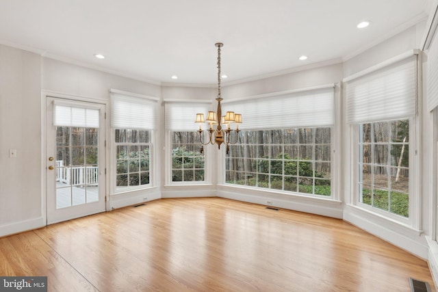 unfurnished dining area with wood finished floors, visible vents, recessed lighting, crown molding, and a notable chandelier