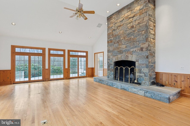 unfurnished living room featuring visible vents, wainscoting, a fireplace, wood finished floors, and high vaulted ceiling