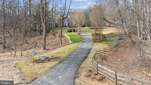 view of property's community with aphalt driveway and fence