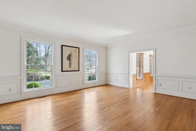 unfurnished room with visible vents, ornamental molding, and wood finished floors