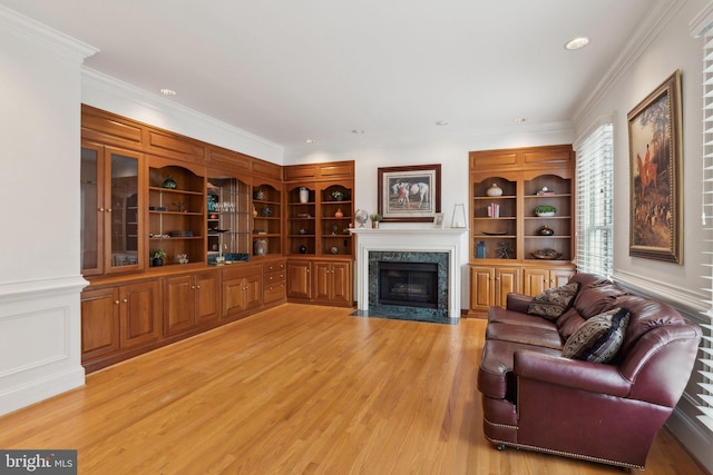 living room featuring light wood-style floors, ornamental molding, and a fireplace