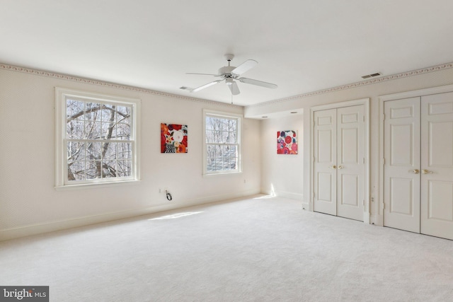 unfurnished bedroom with visible vents, multiple closets, a ceiling fan, carpet flooring, and baseboards