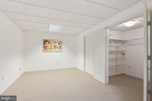 interior space with a paneled ceiling, baseboards, and carpet floors