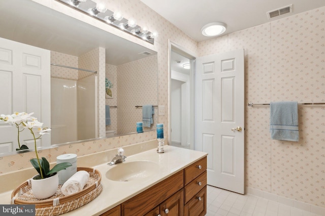 full bathroom with tile patterned floors, visible vents, wallpapered walls, walk in shower, and vanity