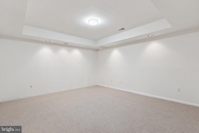 unfurnished room with light carpet, visible vents, and a raised ceiling