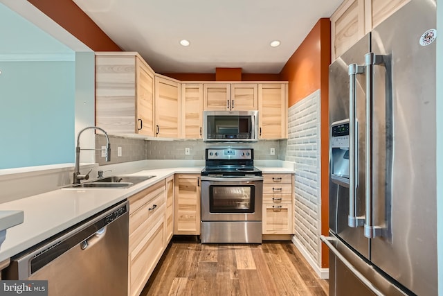 kitchen with light brown cabinetry, backsplash, stainless steel appliances, and a sink