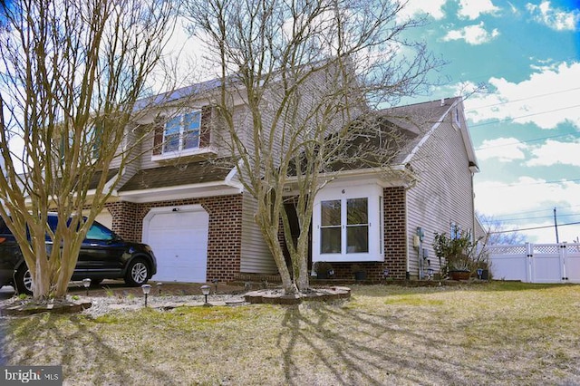 view of front of property featuring an attached garage, fence, and brick siding