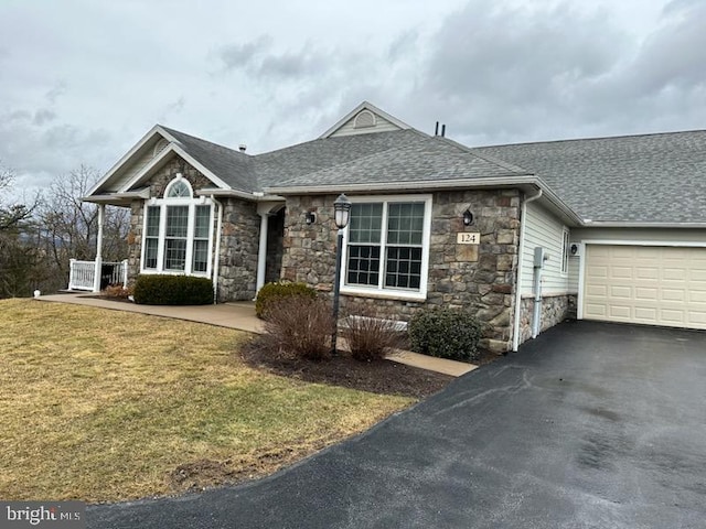 ranch-style house featuring stone siding, driveway, roof with shingles, and a front lawn