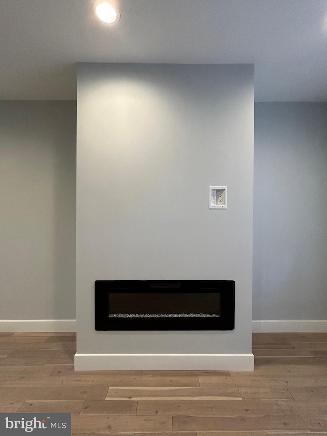 interior details featuring a glass covered fireplace, wood finished floors, and baseboards