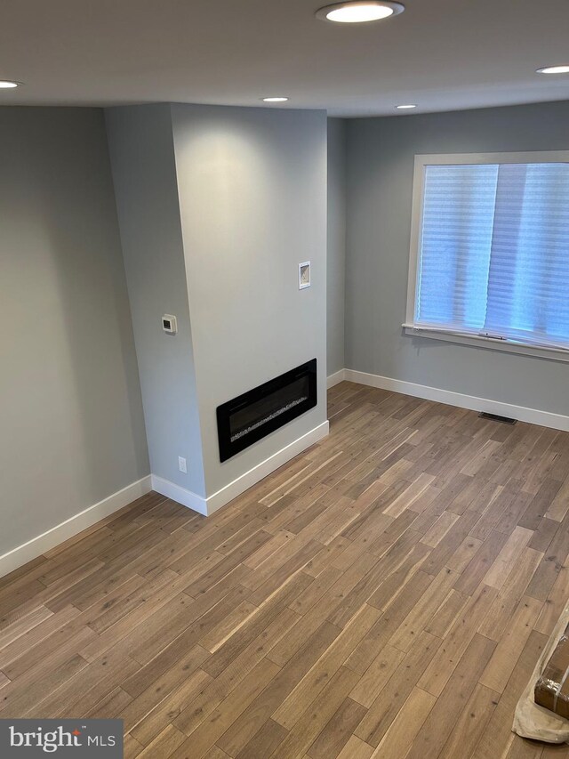 2869 Aramingo Ave, Philadelphia, PA 19134 - unfurnished living room with a glass covered fireplace, visible vents, wood finished floors, and baseboards