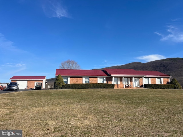 ranch-style house with a mountain view, a front yard, metal roof, and a garage