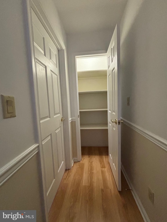 corridor with baseboards and light wood finished floors