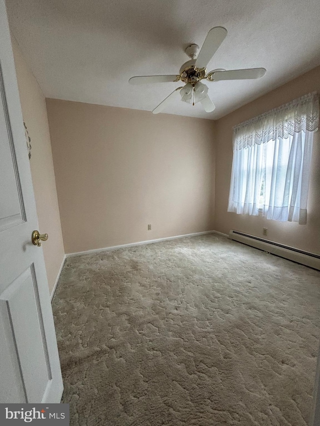 unfurnished room featuring baseboard heating, ceiling fan, baseboards, and carpet floors