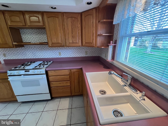 kitchen with a sink, open shelves, white gas range, and brown cabinets
