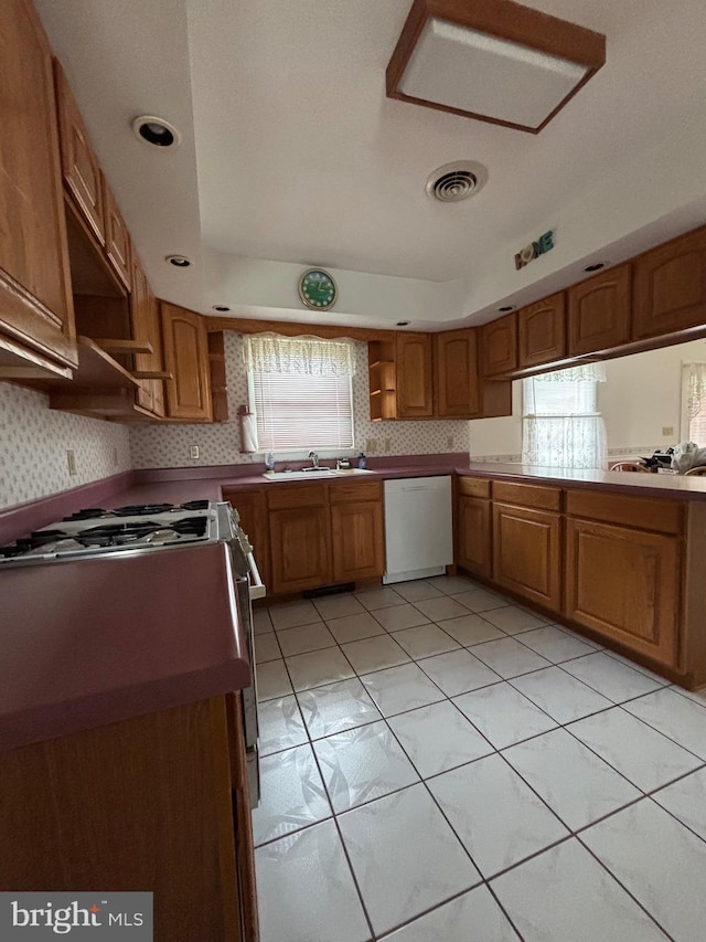 kitchen featuring open shelves, visible vents, brown cabinetry, white dishwasher, and stainless steel range with gas stovetop