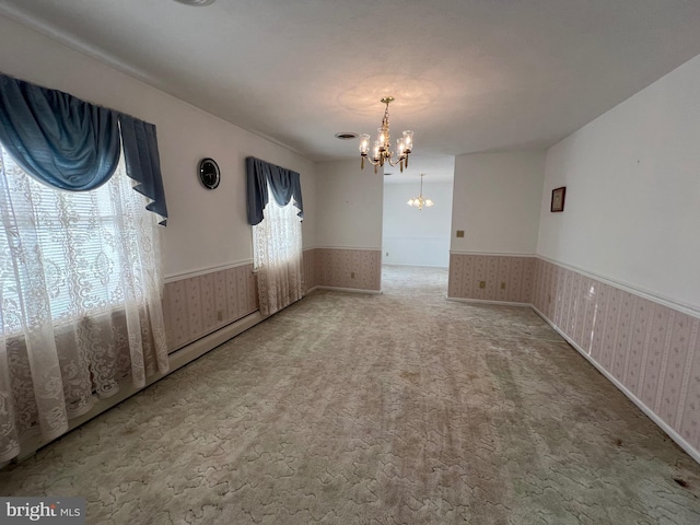 unfurnished dining area with a chandelier, carpet, wainscoting, and wallpapered walls