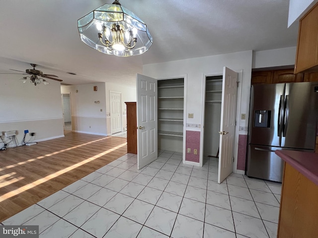kitchen with ceiling fan with notable chandelier, baseboards, and stainless steel refrigerator with ice dispenser